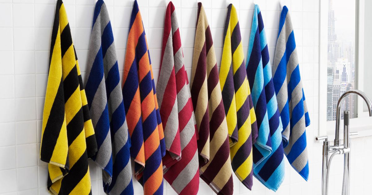 striped rugby towel sets hanging on hooks in a line on the wall