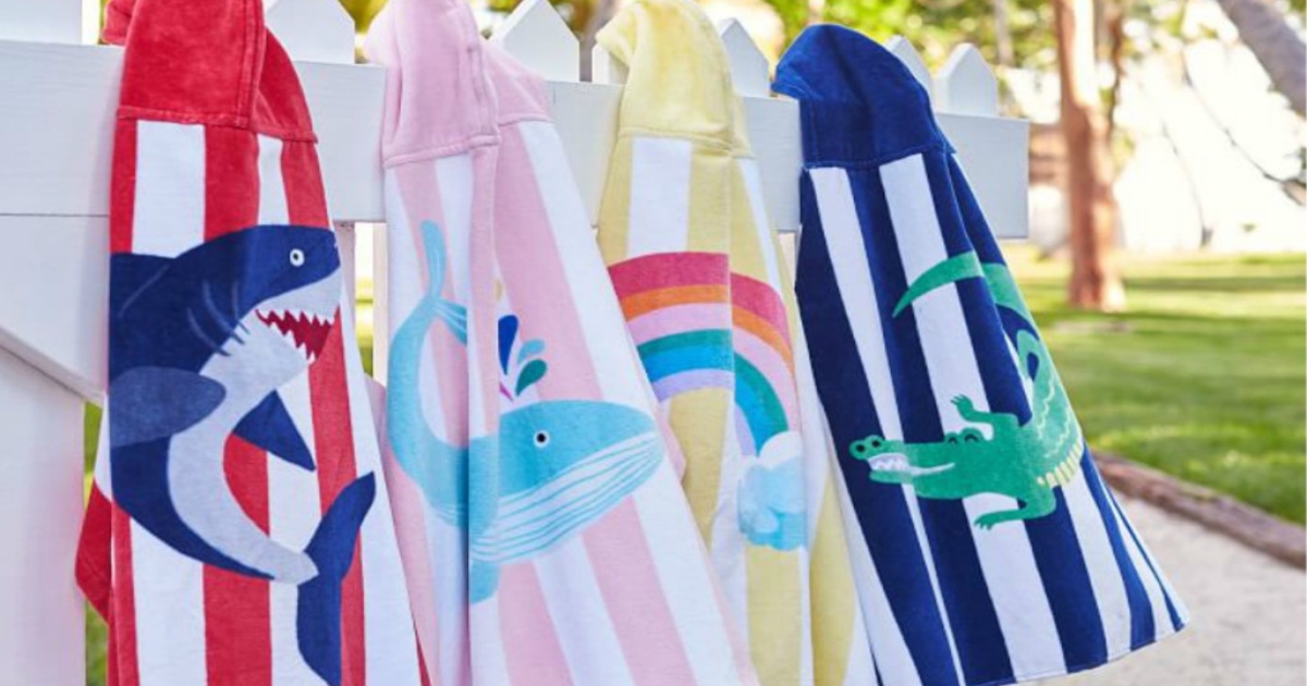 Striped beach towel wraps for babies, hanging side by side on a white fence outside