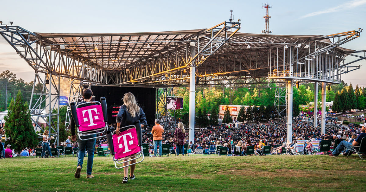 2 people carrying t-mobile chairs to a concert venue