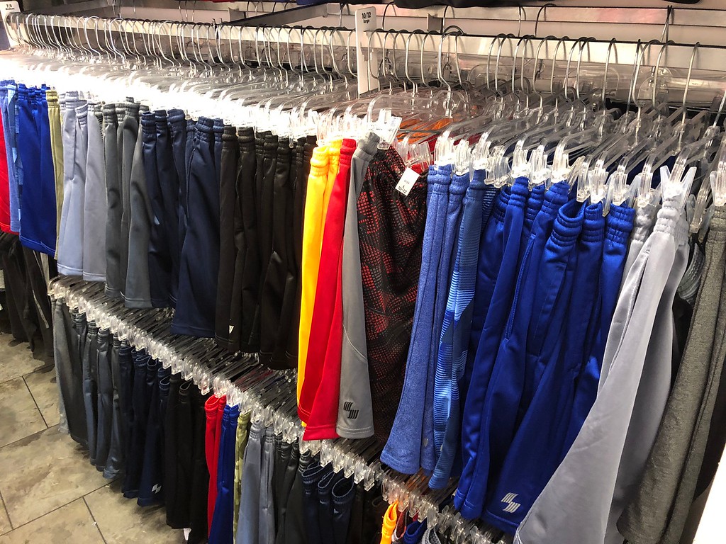 Several styles of boys basketball shorts hanging on a rack