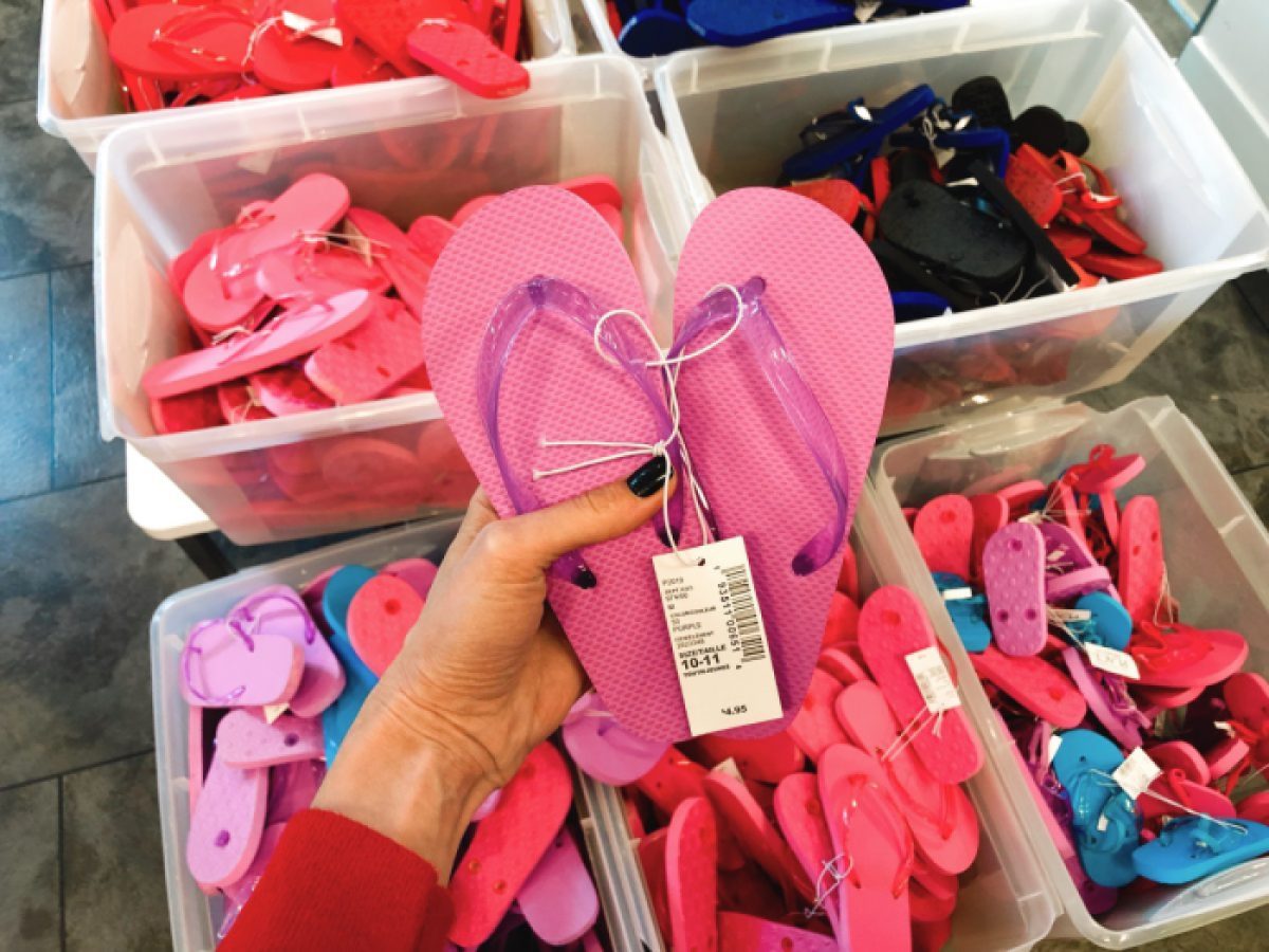 Woman holding The Children's Place pink flip flop over bin