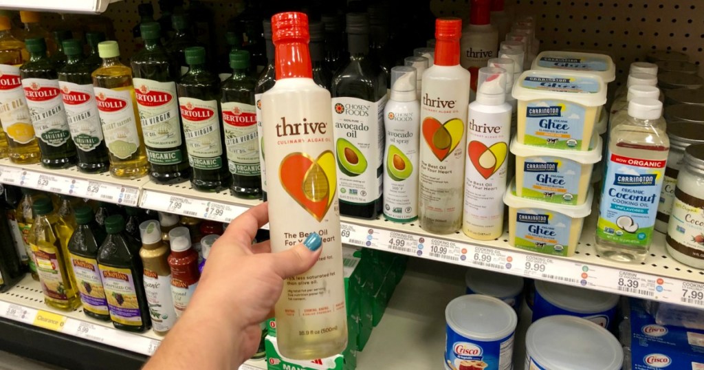 hand holding up thrive cooking oil in store in front of other oils on the shelf