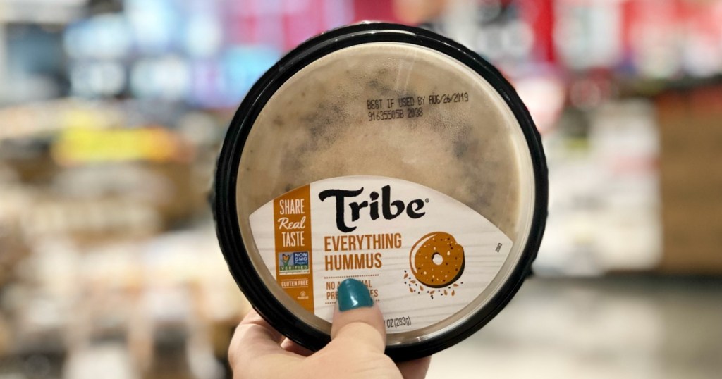 hand holding tribe hummus with blurred background