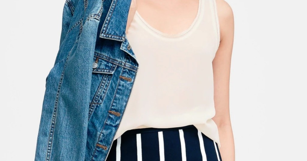 woman wearing white tank top blouse with jean jacket over shoulder