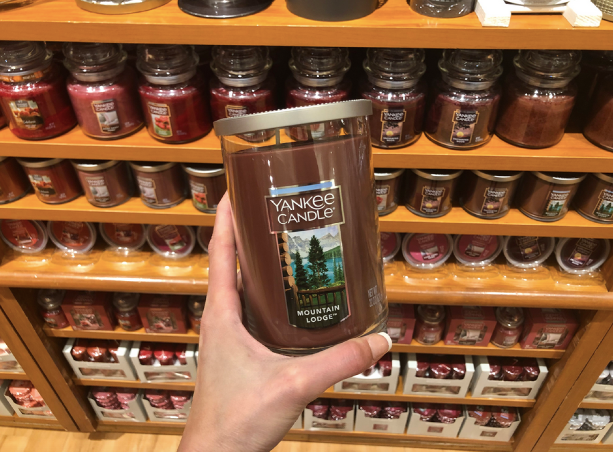 woman holding Yankee Candle Mountain Lodge 2-wick candle in front of other candles