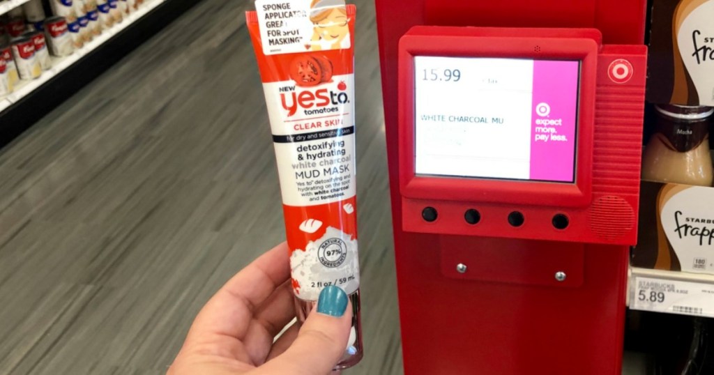 Hand holding Yes to Tomatoes White Charcoal mud mask bottle next to Target price scanner