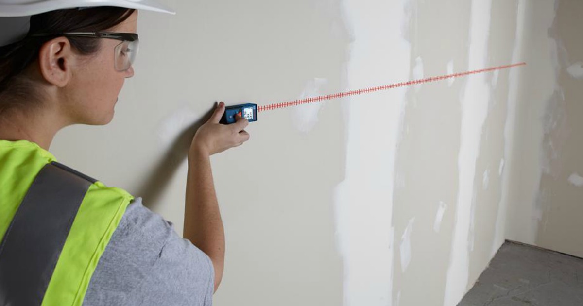 woman using laser to measure drywall