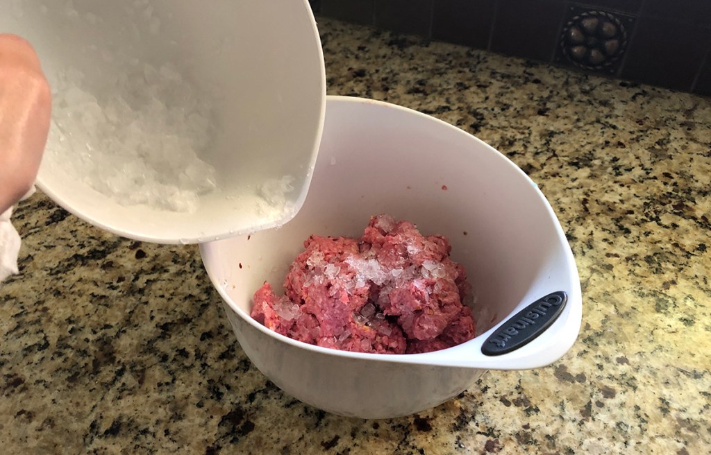 pouring in crushed ice to ground beef for burgers