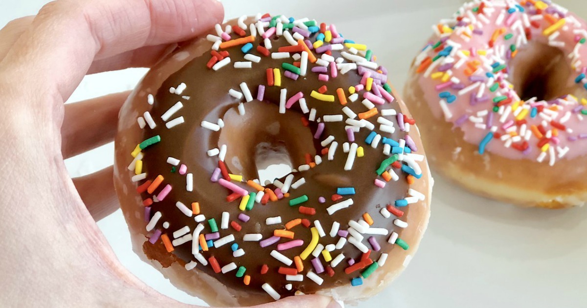 krispy kreme doughnut in person's hand with sprinkles