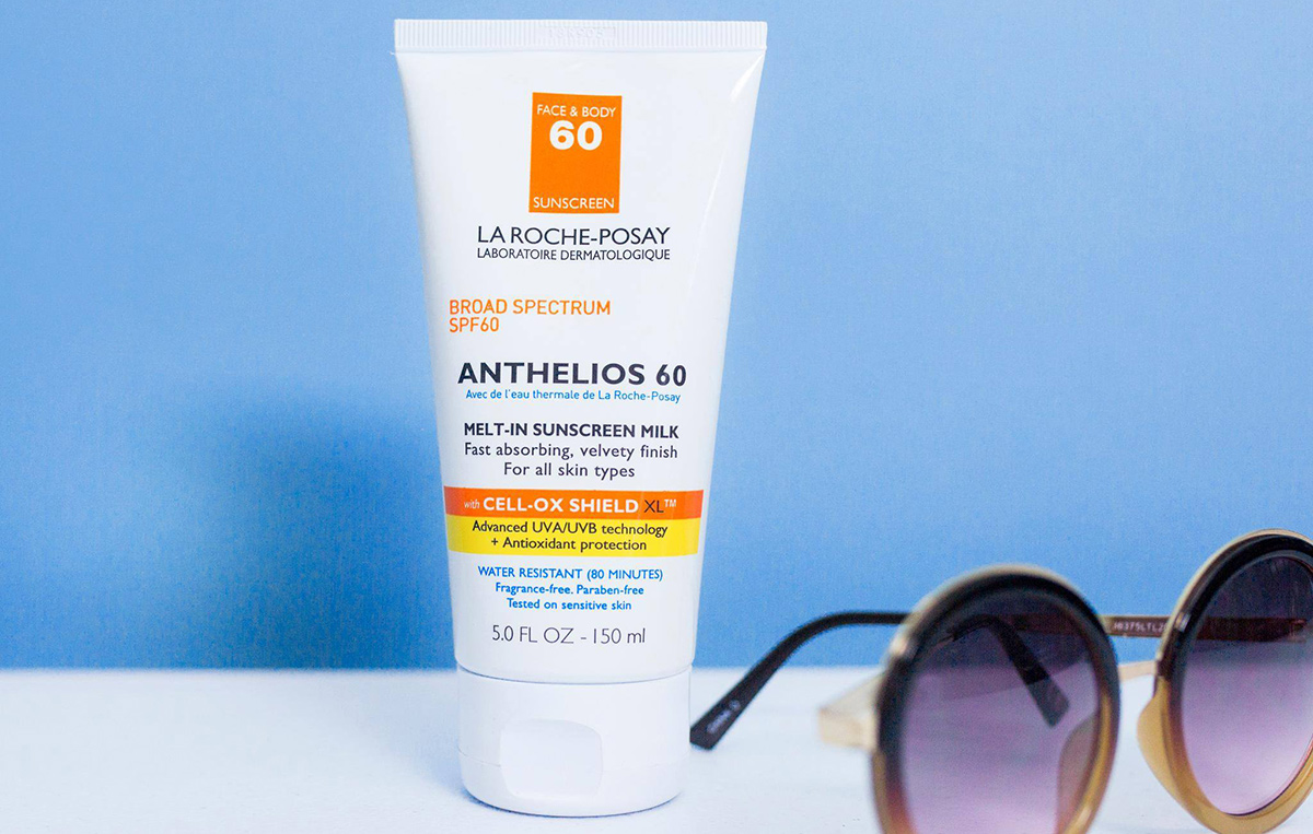 la roche posay anthelios sunscreen with blue background and sunglasses on table