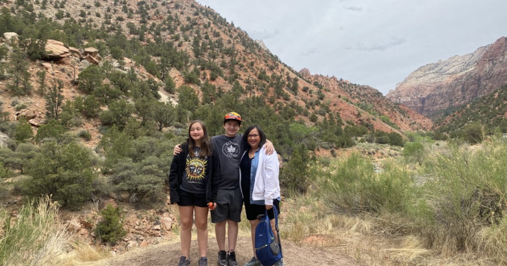 three people standing in front of valley in zion national park