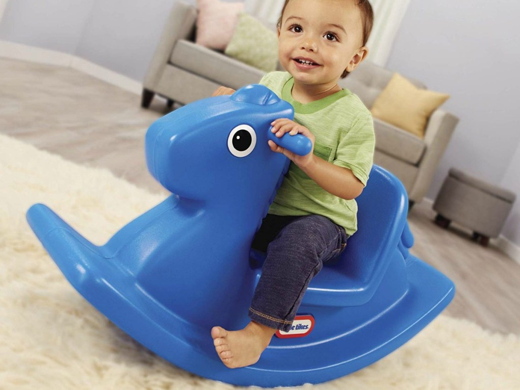 little boy on blue rocking horse in house