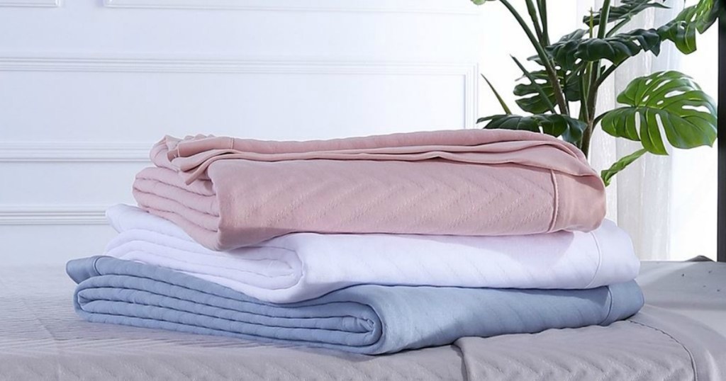 three colored blankets on a bed