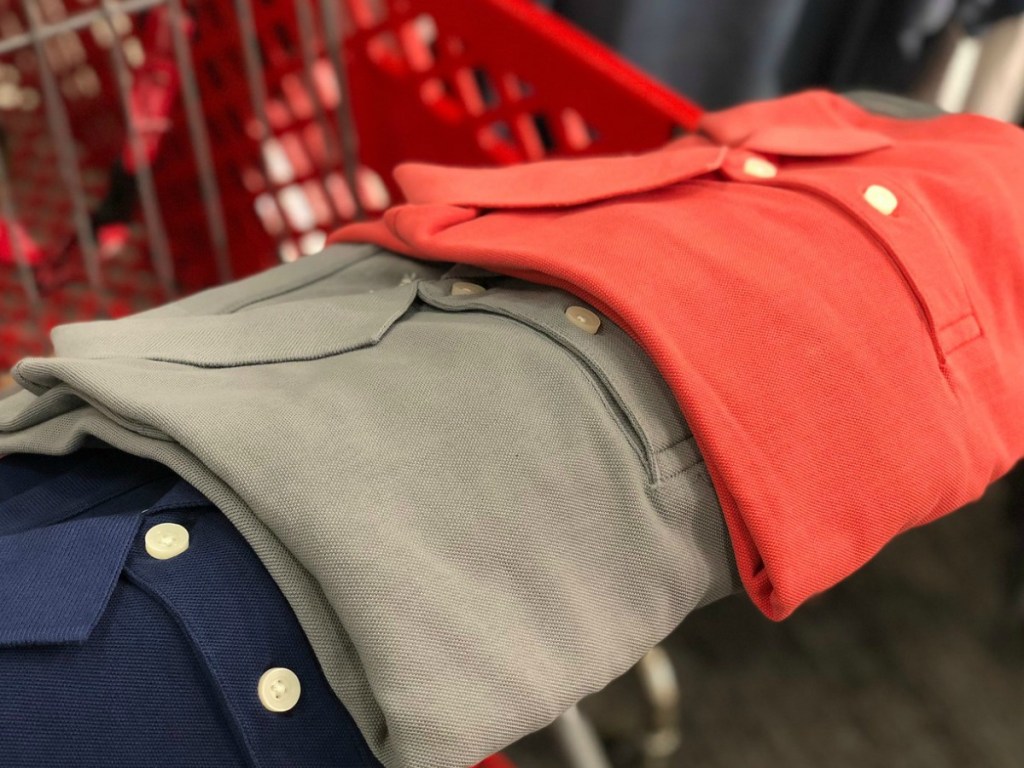 three various polo shirts laying on a shopping cart