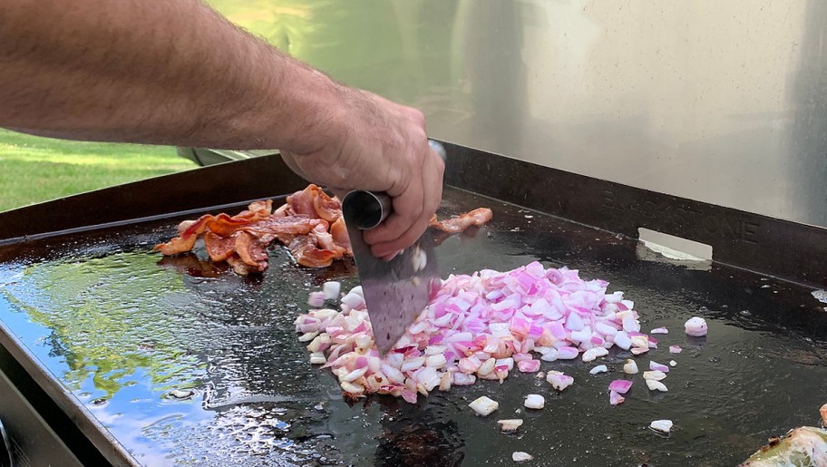 man cooking onions on blackstone griddle