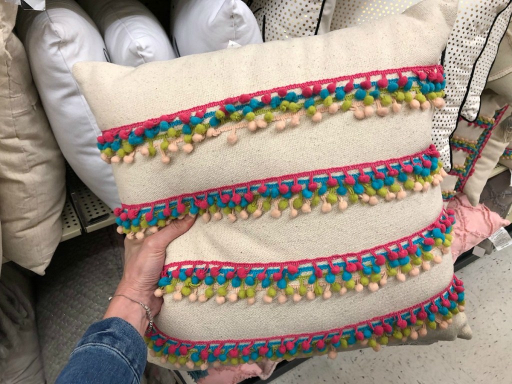 cream colored throw pillow with multi-colored fringe