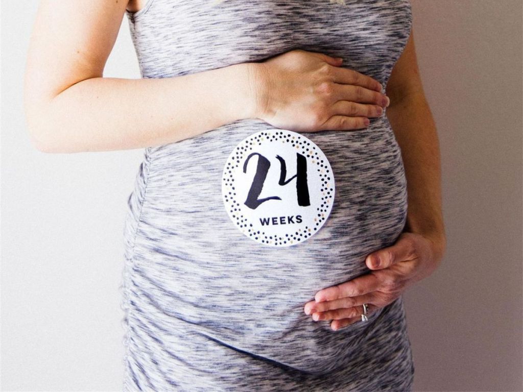woman in grey heathered tank top wearing 24 week pregnancy sticker