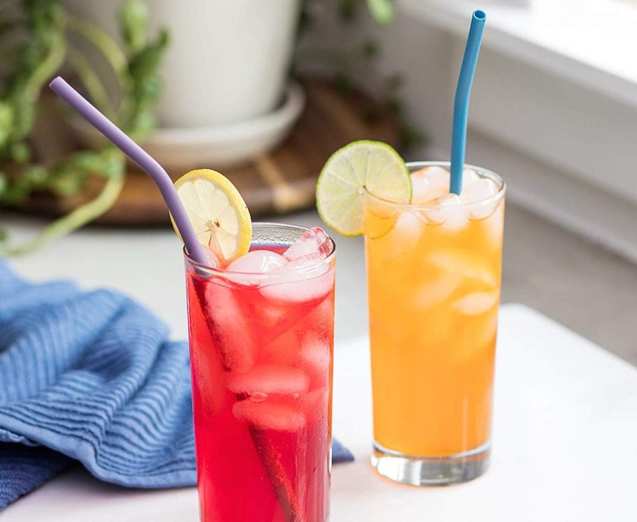 two glasses with red and orange iced drinks and straws