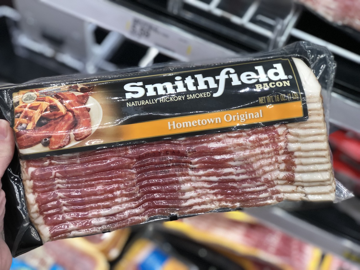 hand holding smithfield hometown original bacon in meat case