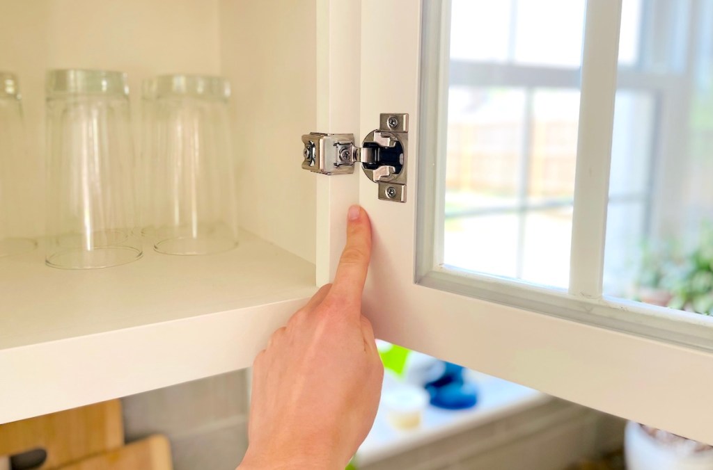 hand pointing to soft closing hinge on kitchen cabinet door