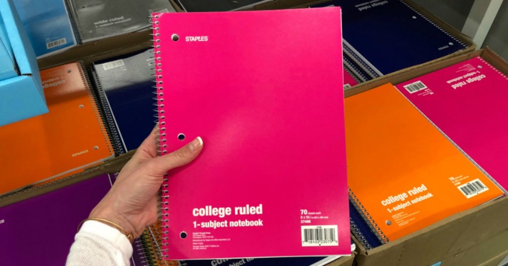 hand holding pink staples college ruled notebook