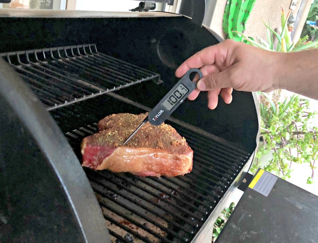 taking temp of steak on grill 