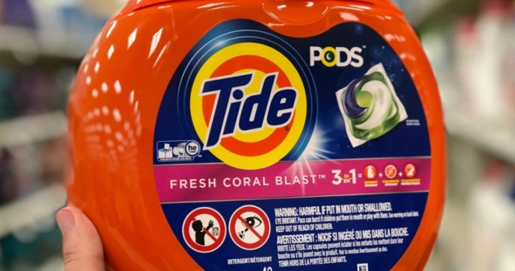 Hand holding up tide pods detergent in store aisle