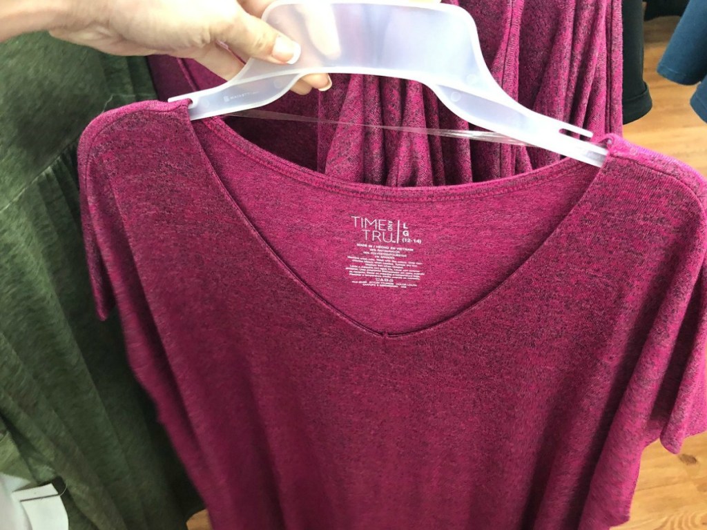 hand holding pink dress on hanger in store