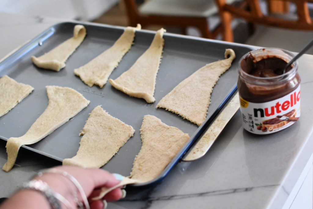 unrolling crescent dough on a caraway sheet pan