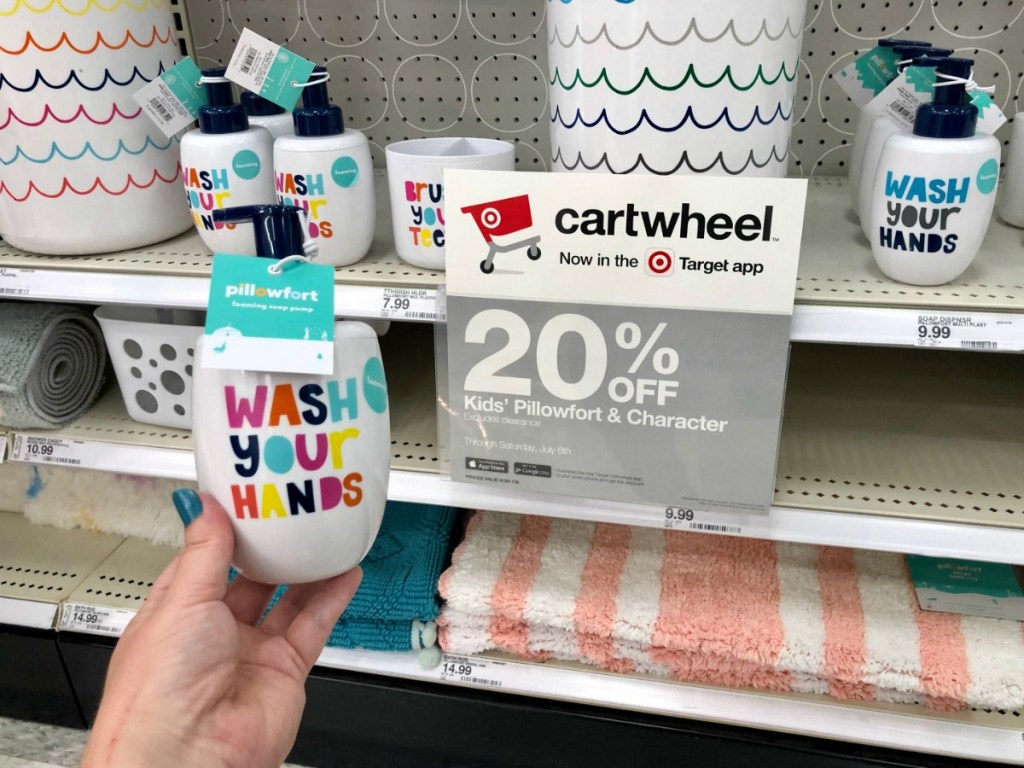 hand holding wash your hands soap dispenser in front of cartwheel sign