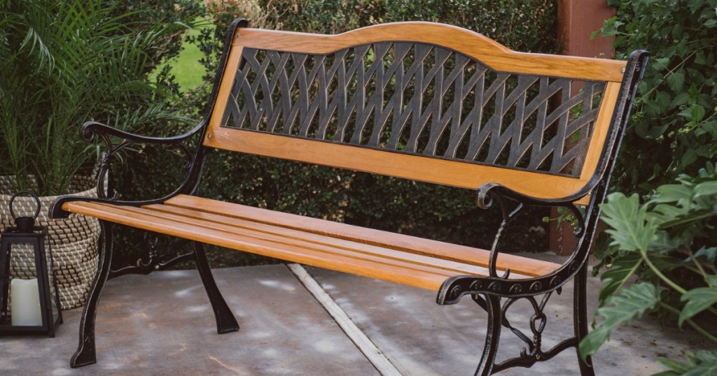 brown wood and black metal curved back bench sitting outside