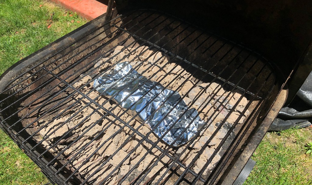 packet of wood chips underneath grill grates 