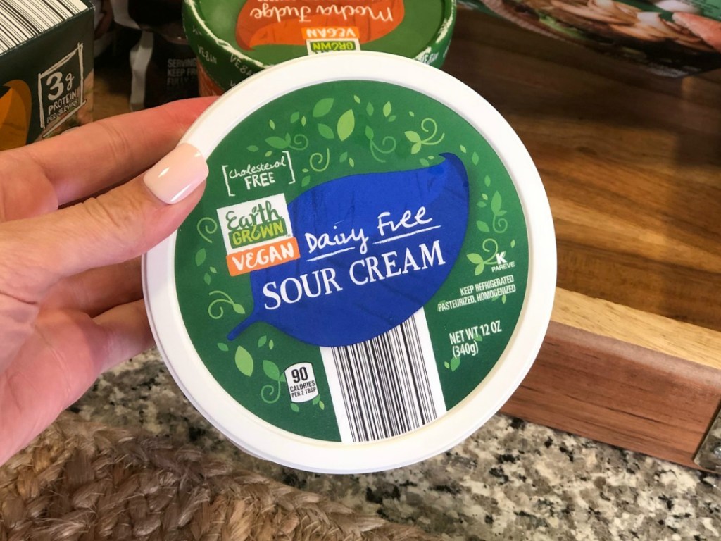 ALDI Vegan Sour Cream held up over kitchen counter