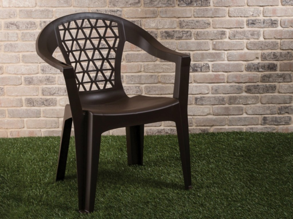 plastic brown chair outside on grass by brick wall