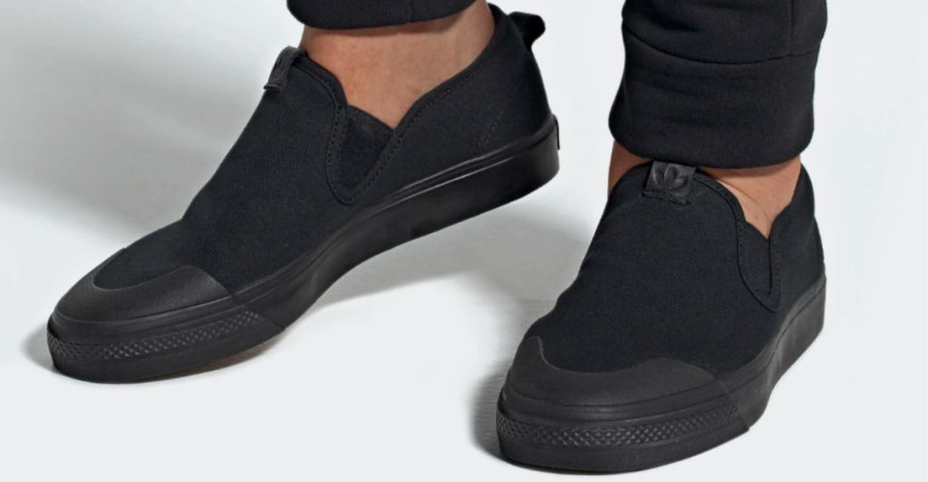 person wearing adidas black nizza slip on shoes