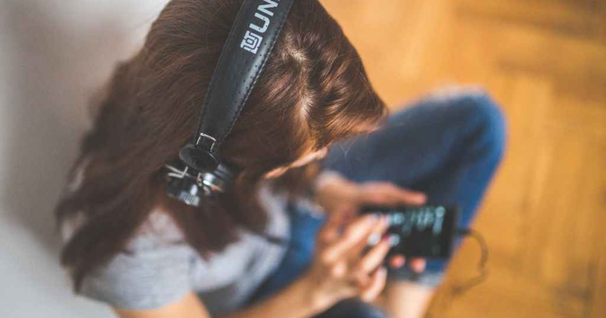 woman wearing headphones listening to music on her smart phone