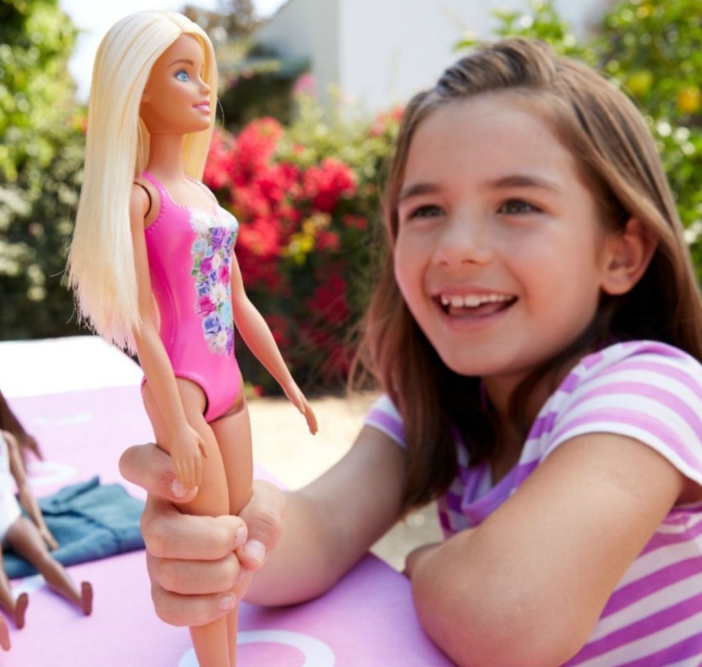 Young girl playing with beach Barbie doll