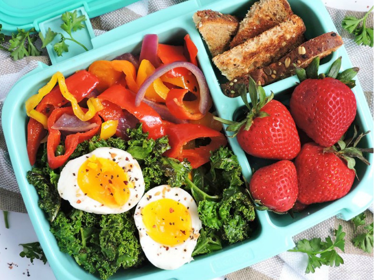 Bentgo Bento container filled with salad, peppers, eggs, strawberries and whole grain bread