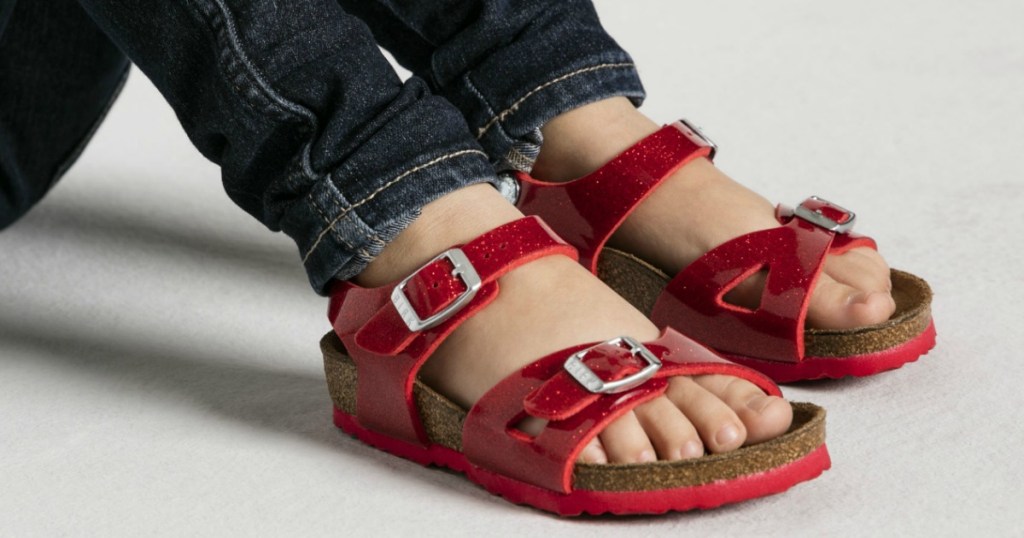 girl sitting with knees up wearing Magic Red Birkenstocks Rio Kids sandals 