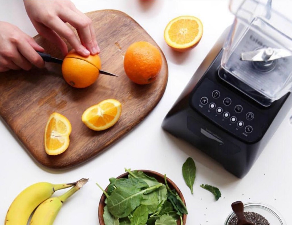 Blendtec blender in black with ingredients - oranges, spinach, banana, chia seeds