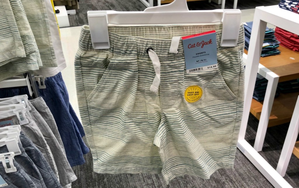 Pair of boys' shorts with green stripes on white hanger in store