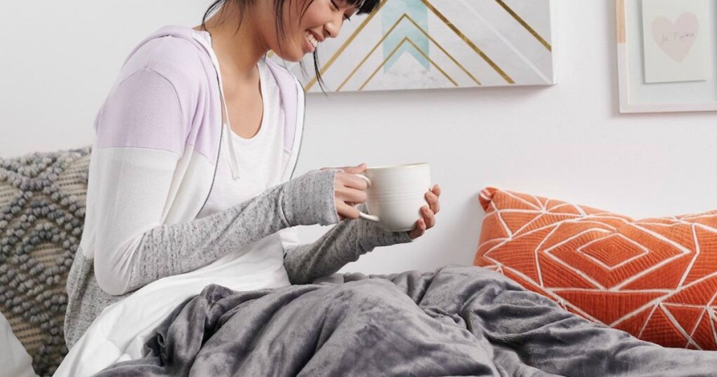 woman sitting on bed drinking coffee