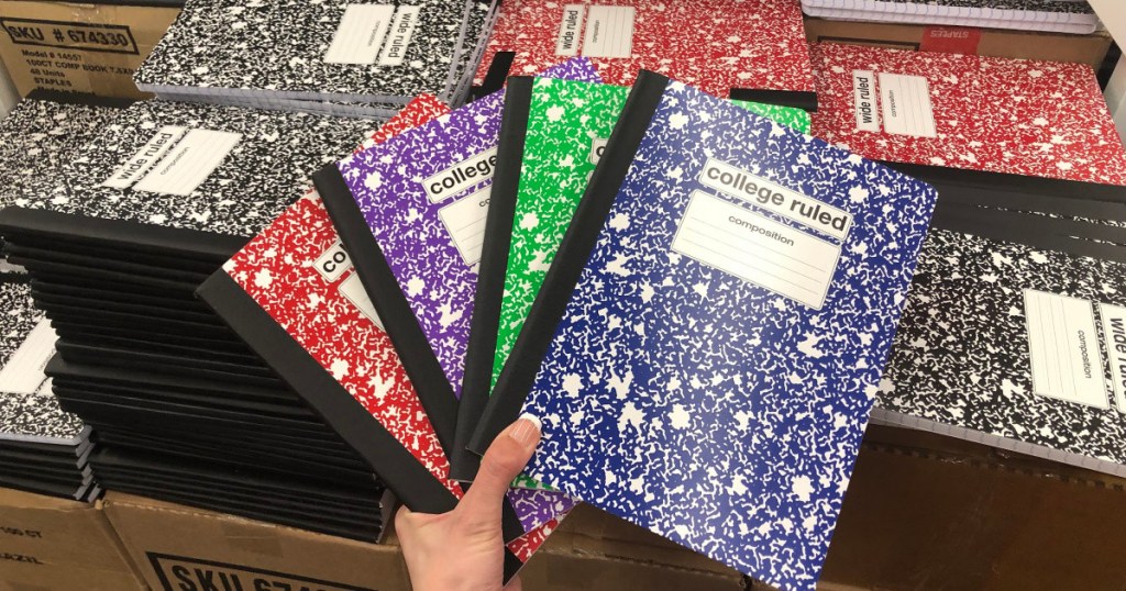 hand holding four colors of composition notebooks fanned out