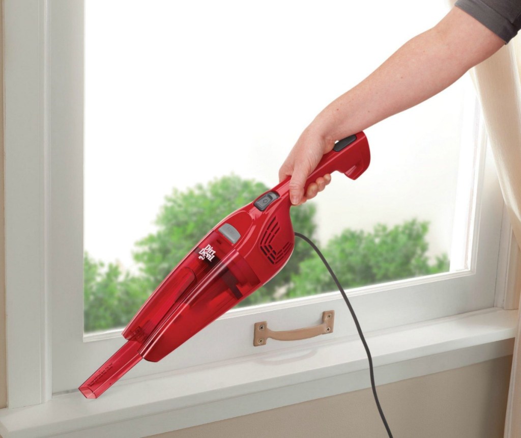Red handheld vacuum being used on a window