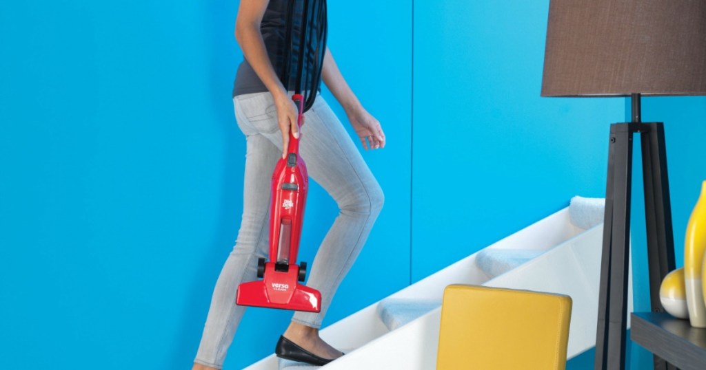 Woman carrying a red vacuum up white stairs