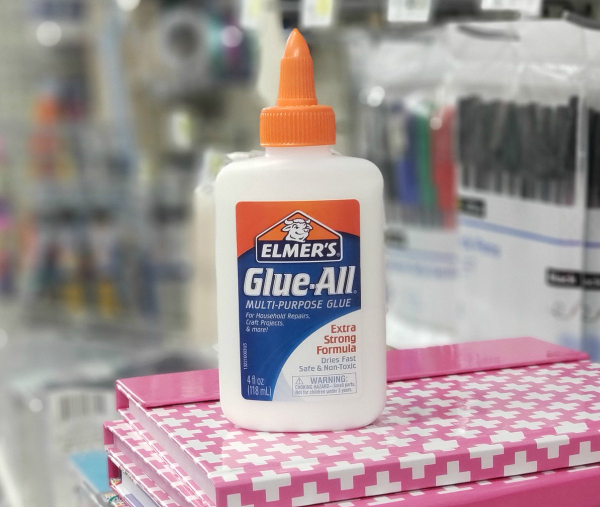 Bottle of glue on top of stack of school supplies in store