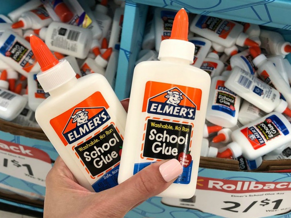 hand holding two bottles of glue by store display