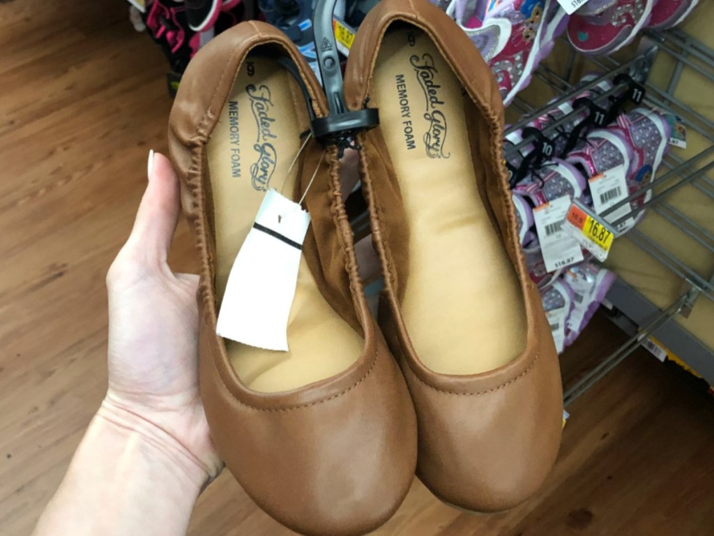 hand holding pair of brown shoes for women