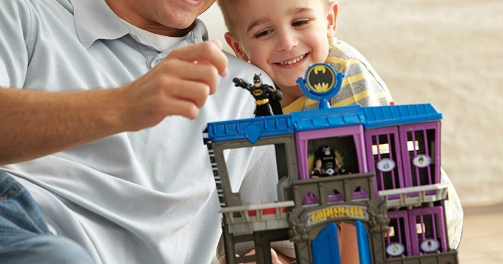 child and father playing with a batman playset