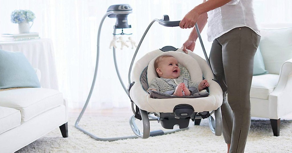 Mother carrying detachable seat from Graco swing with infant inside